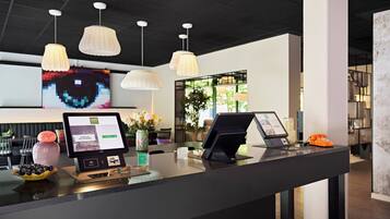A modern reception desk with digital kiosks, pendant lighting, and a pixel art wall.