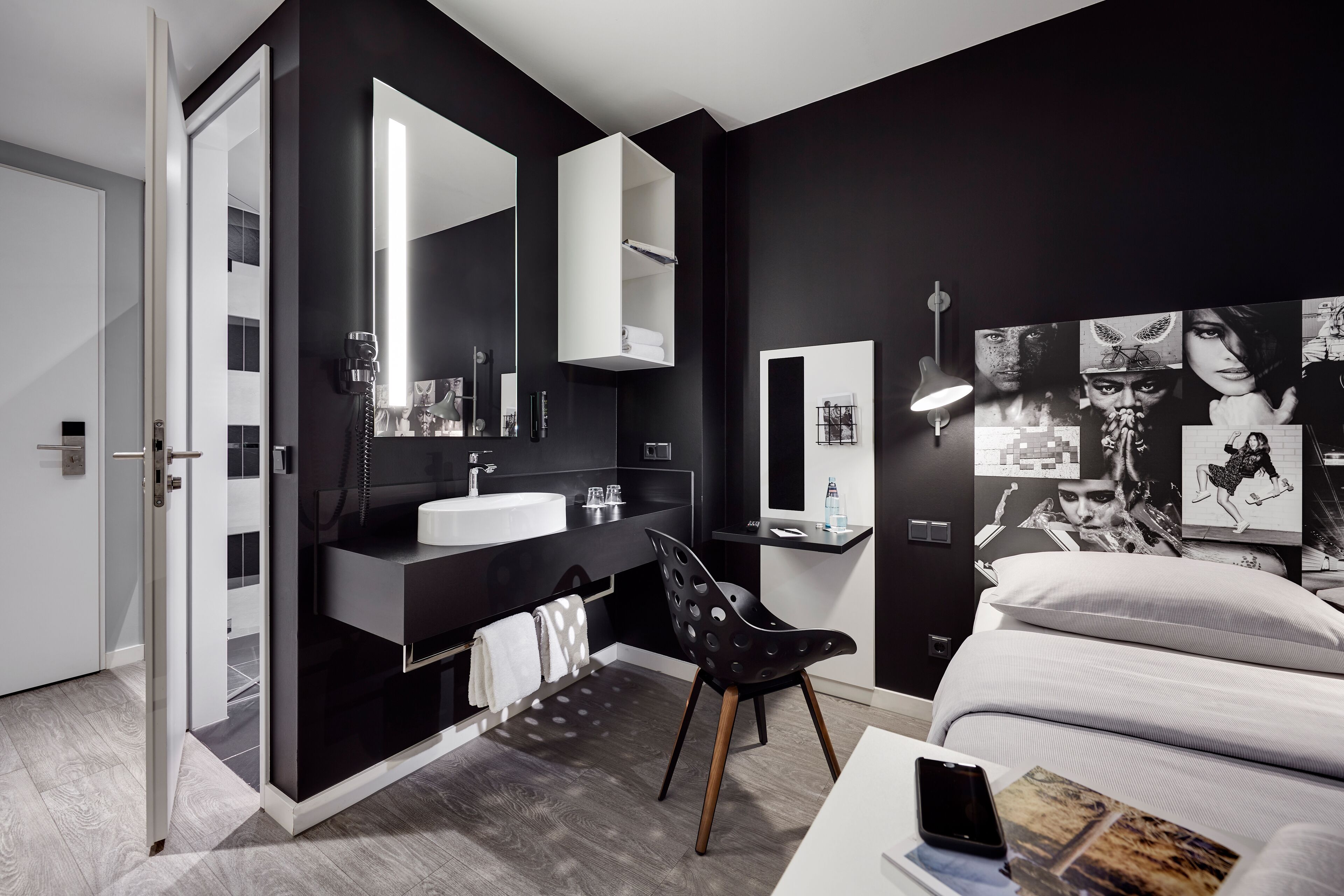 A modern bathroom with a large mirror, white sink, and black vanity.