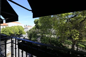 A balcony with a view of a tree-lined street and buildings. - Charm Flats (Lisbon)