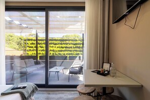 A modern room with a glass door leading to an outdoor area with a view of a vineyard. - Charm Flats (Lisbon)