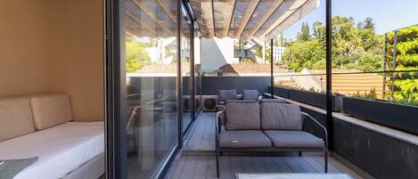 A balcony with a sofa, a small table, and a glass partition.