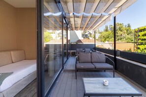 A balcony with a sofa, a small table, and a glass partition.