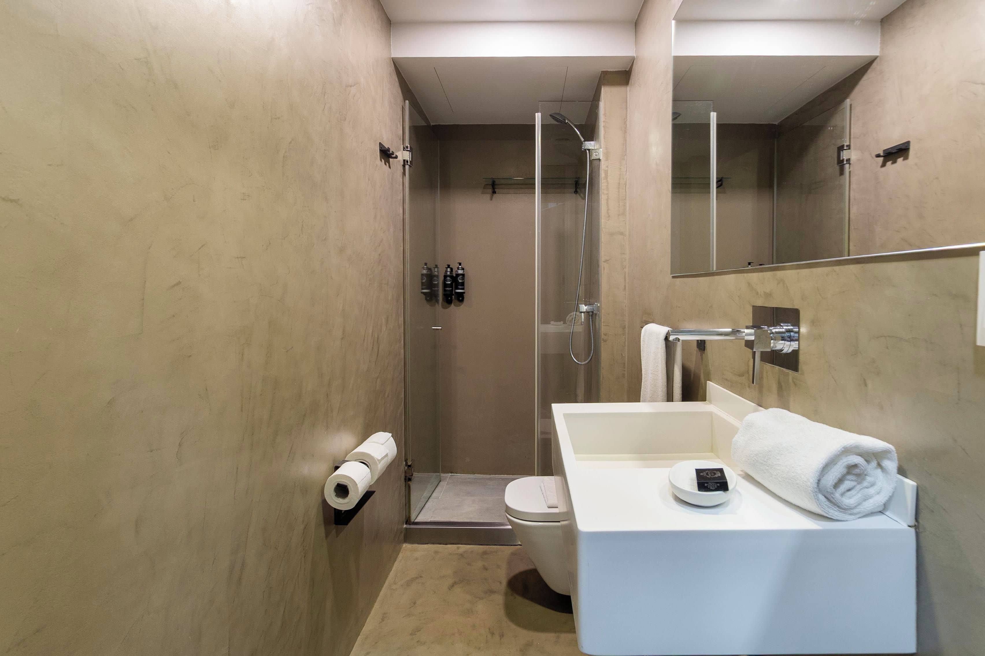 A modern bathroom with a glass-enclosed shower, a white sink, and a toilet.