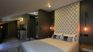 A modern hotel room with a large bed, a tufted headboard, a bedside table, and a small desk area with a chair.