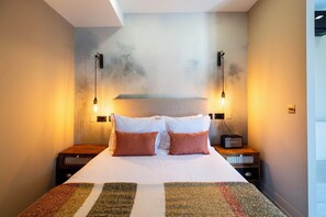 A neatly made bed with two pillows, a wall-mounted shelf above, and two bedside tables with lamps. - Charm Flats (Lisbon)