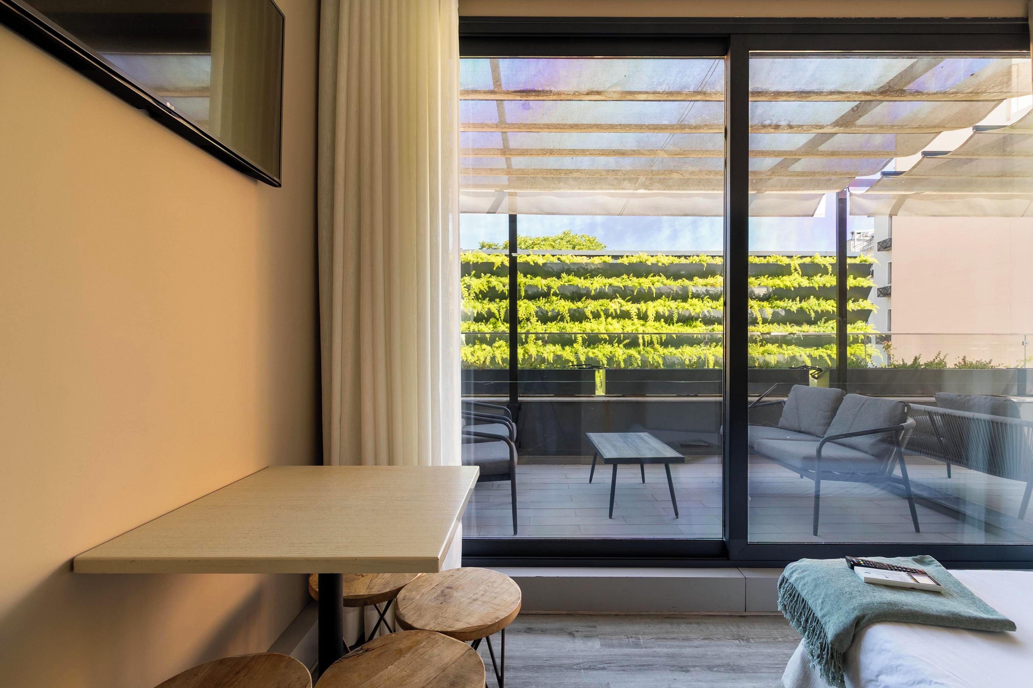 A modern room with a large window, a table, chairs, and a bed.