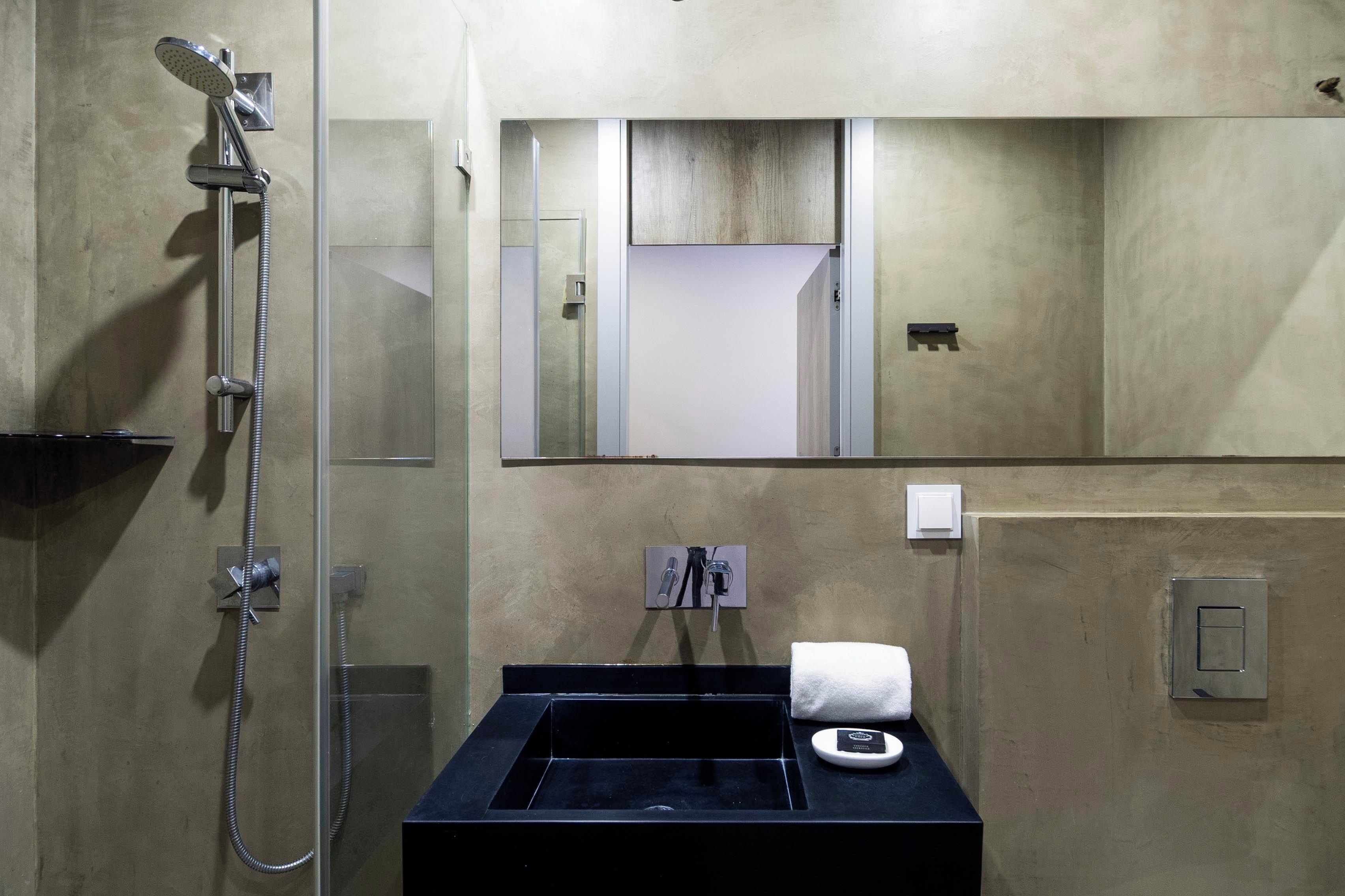 Un baño con ducha, lavabo, espejo y toalla.