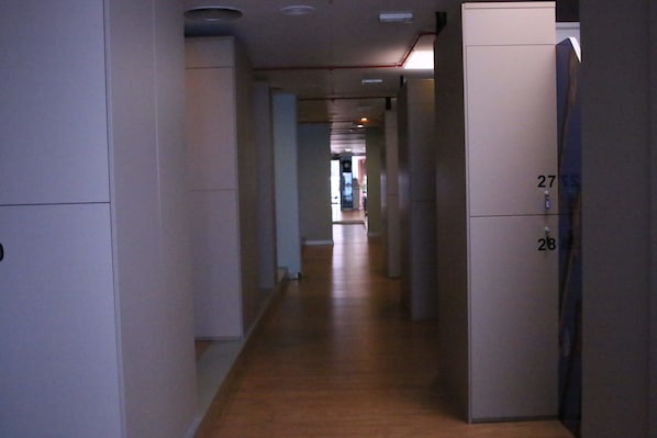 A corridor with a wooden floor and white walls, leading to a door marked with the number 27.