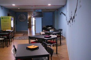 A conference room with tables and chairs, a large screen, and a wall with a graph.