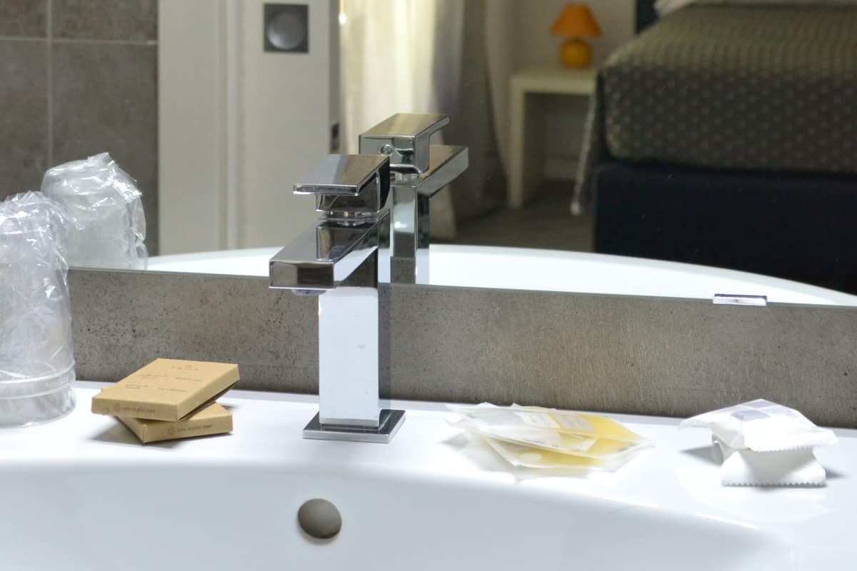 A bathroom with a sink, mirror, and toiletries.