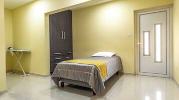 A bedroom with a bed, a wardrobe, a door, and a small table.