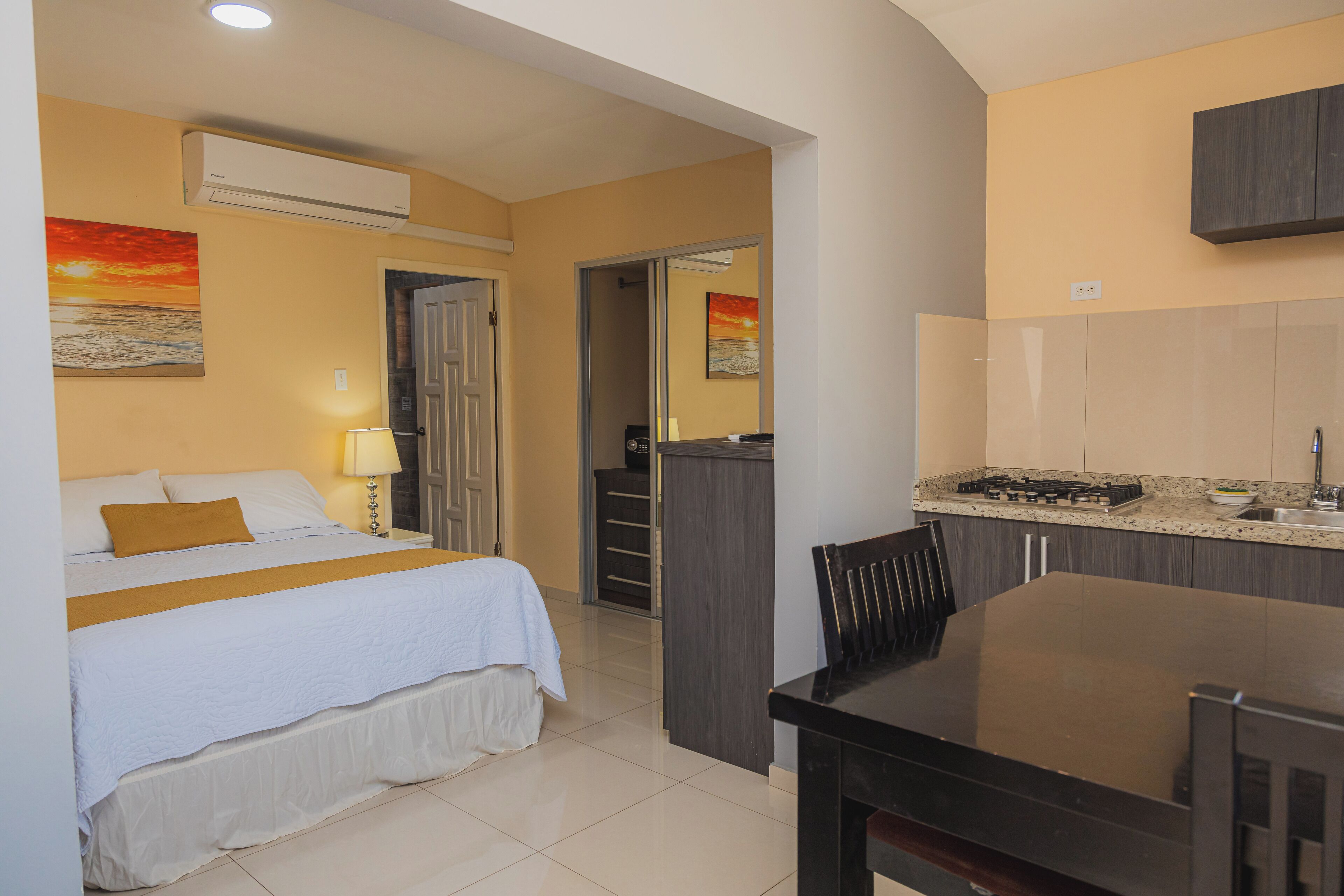 Una habitación de hotel con cama, escritorio y kitchenette.