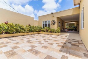 A spacious outdoor area with a checkered floor, potted plants, and a clock on the wall. - Juanedu Suites (Oranjestad)