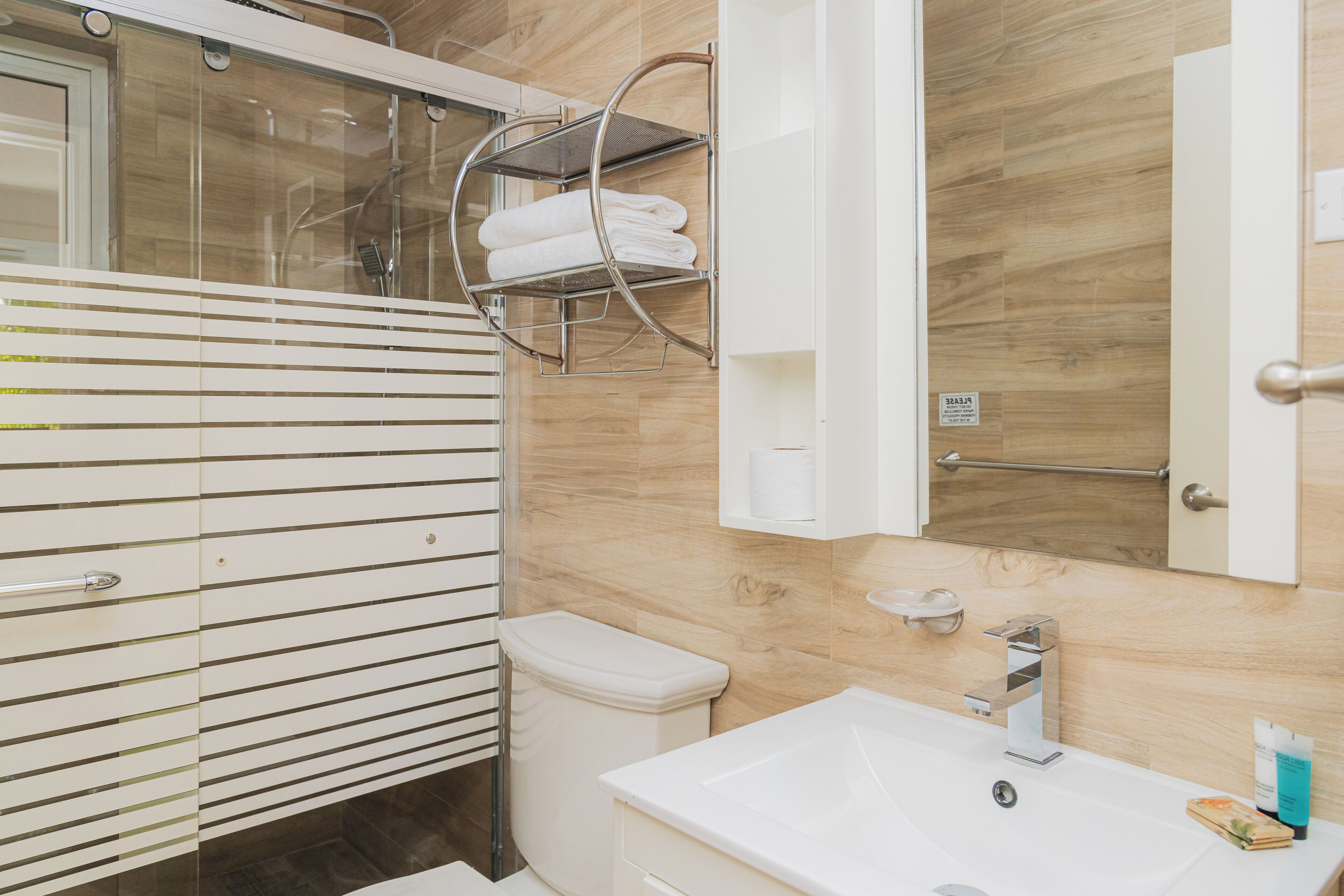 Een moderne badkamer met een wit wastafel, toilet en douchehoek.