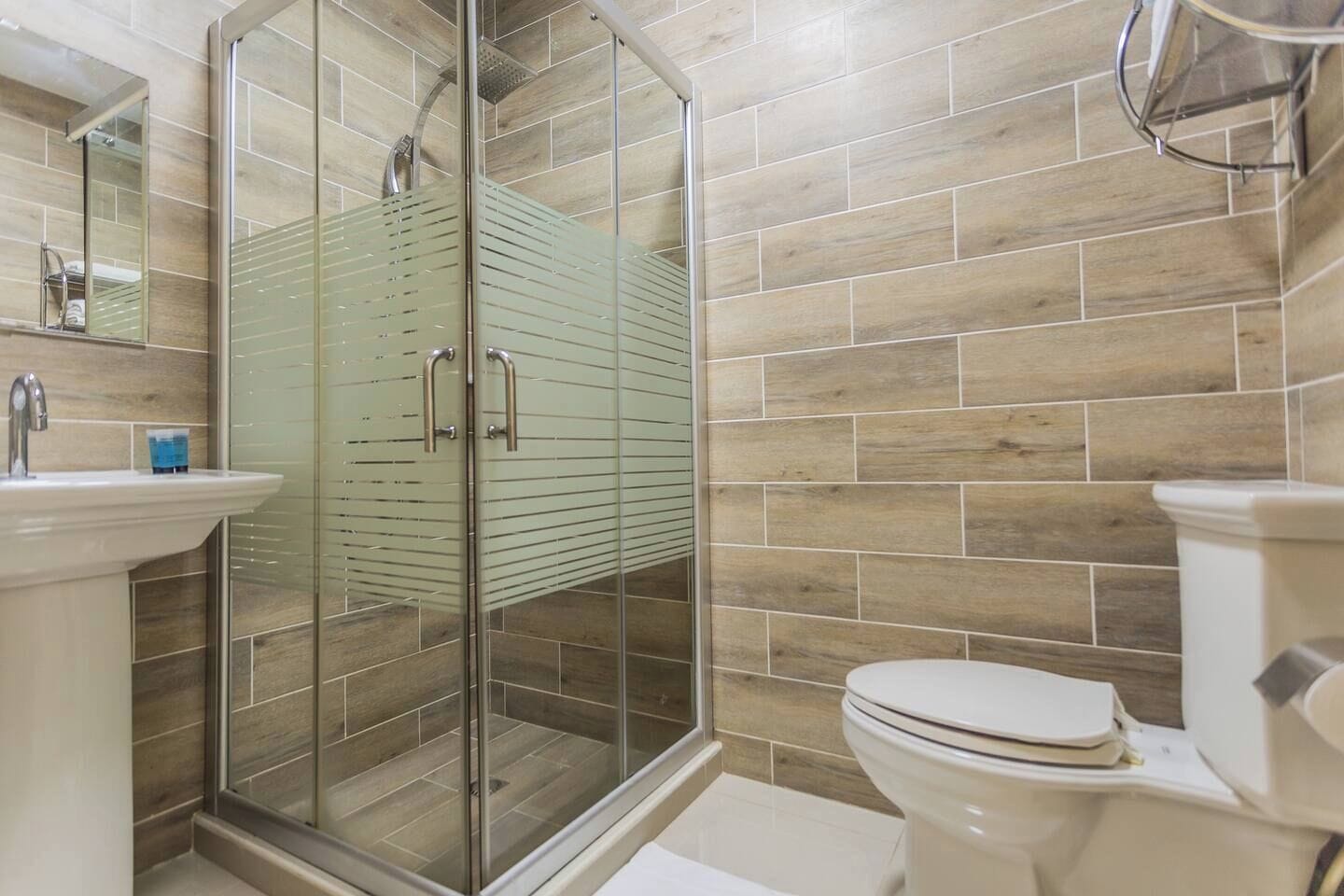 A bathroom with a glass shower enclosure, a sink, and a toilet.