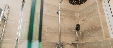 A shower with a handheld showerhead and a wall-mounted faucet.