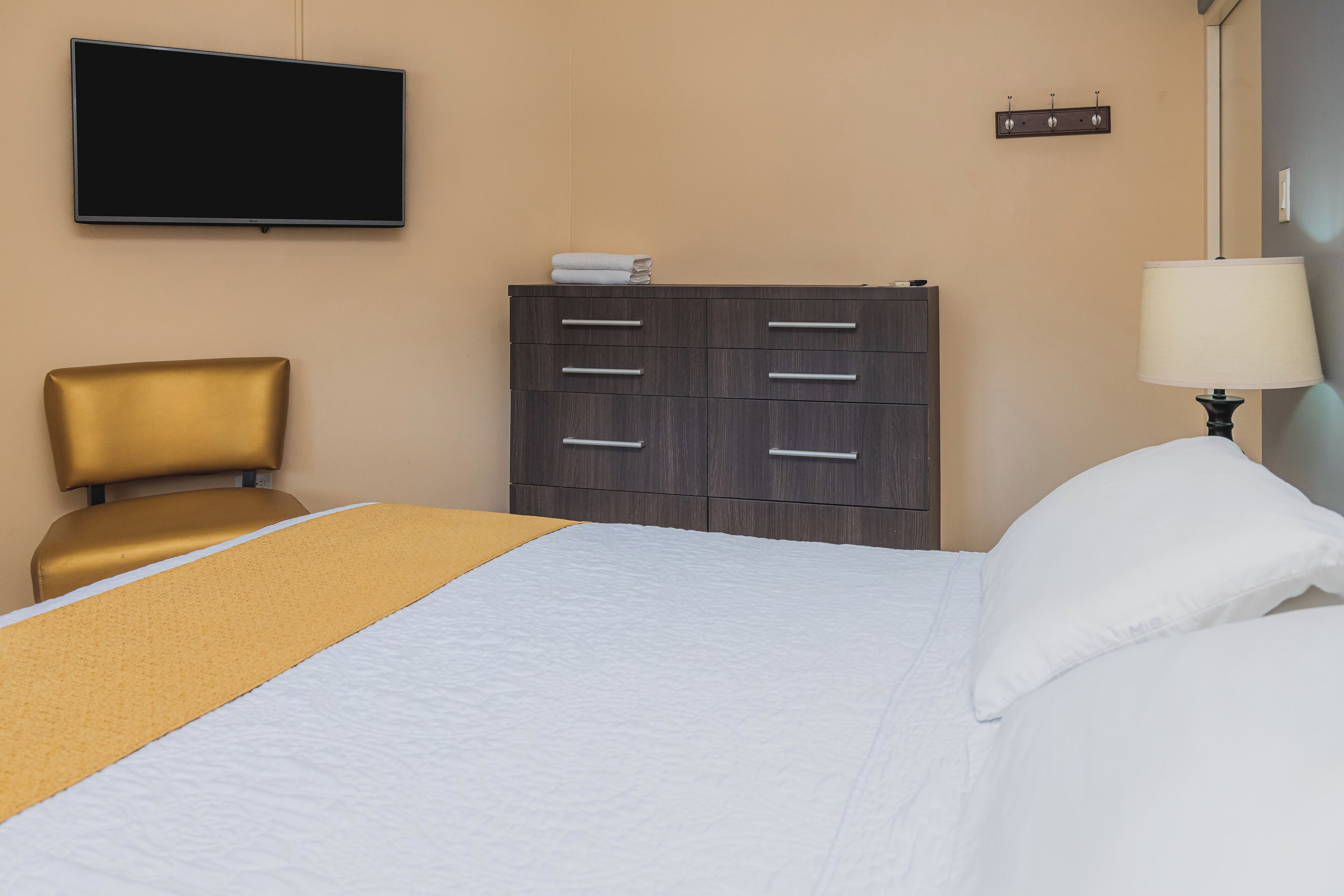Una habitación de hotel con una cama, un aparador de madera, un televisor y una lámpara.