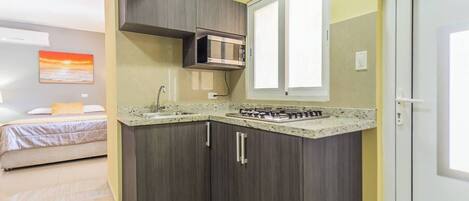 A compact kitchen with dark wood cabinets, a stainless steel microwave, and a gas stove.