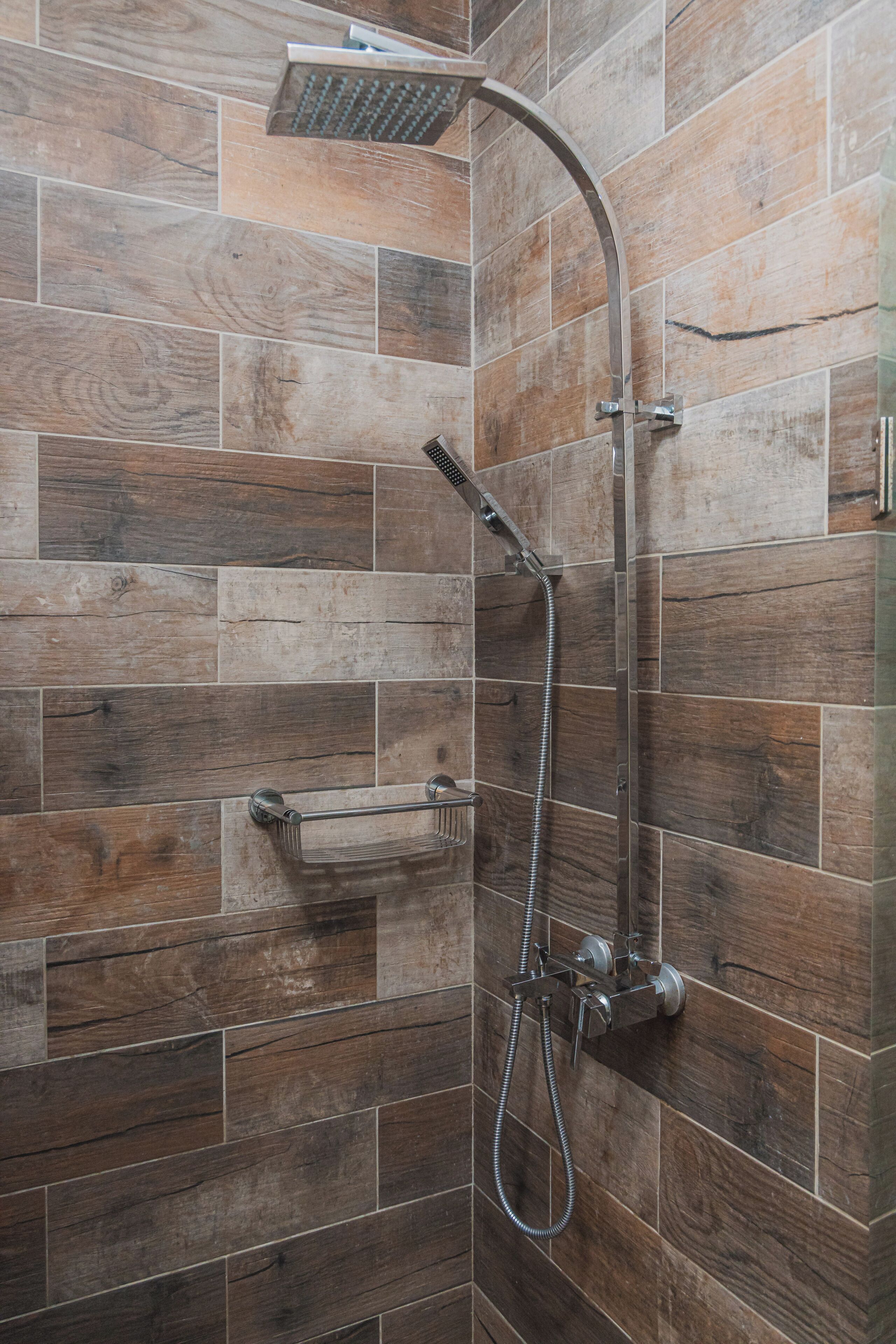A shower with a curved showerhead and a handheld shower attachment.