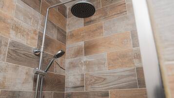 Ducha con cabezal de ducha de mano y cabezal de ducha fijo, sobre un fondo de azulejos con diseño de madera.
