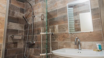 Un baño con ducha, lavamanos y espejo.