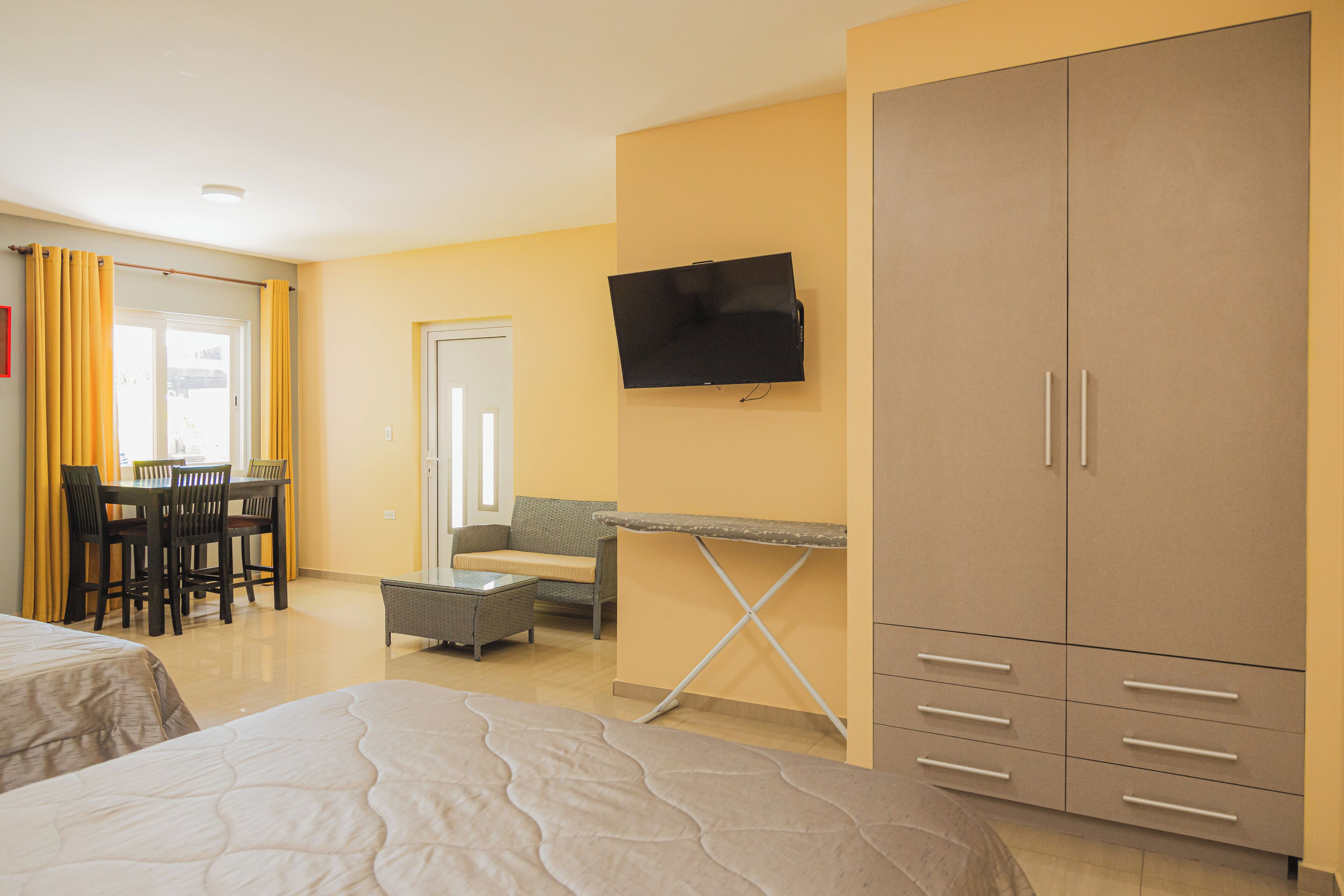 A hotel room with a bed, a desk, a TV, and a wardrobe.