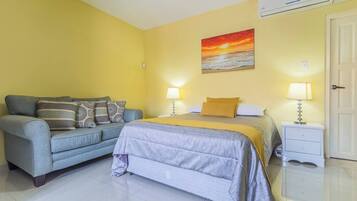A bedroom with a bed, a sofa, two bedside tables, and a painting on the wall.
