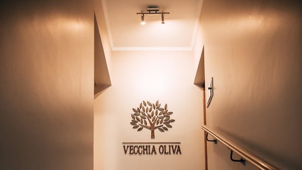 Una escalera con un cartel que dice "VECCHIA OLIVA" y un símbolo de árbol.