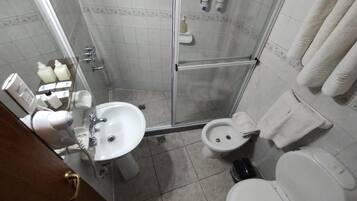 Un baño pequeño con ducha, inodoro y lavamanos.
