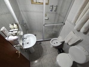 Casa de banho compacta com chuveiro, sanita e lavatório.