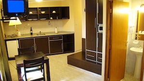 Una cocina compacta con televisor, una mesa de comedor y una silla.