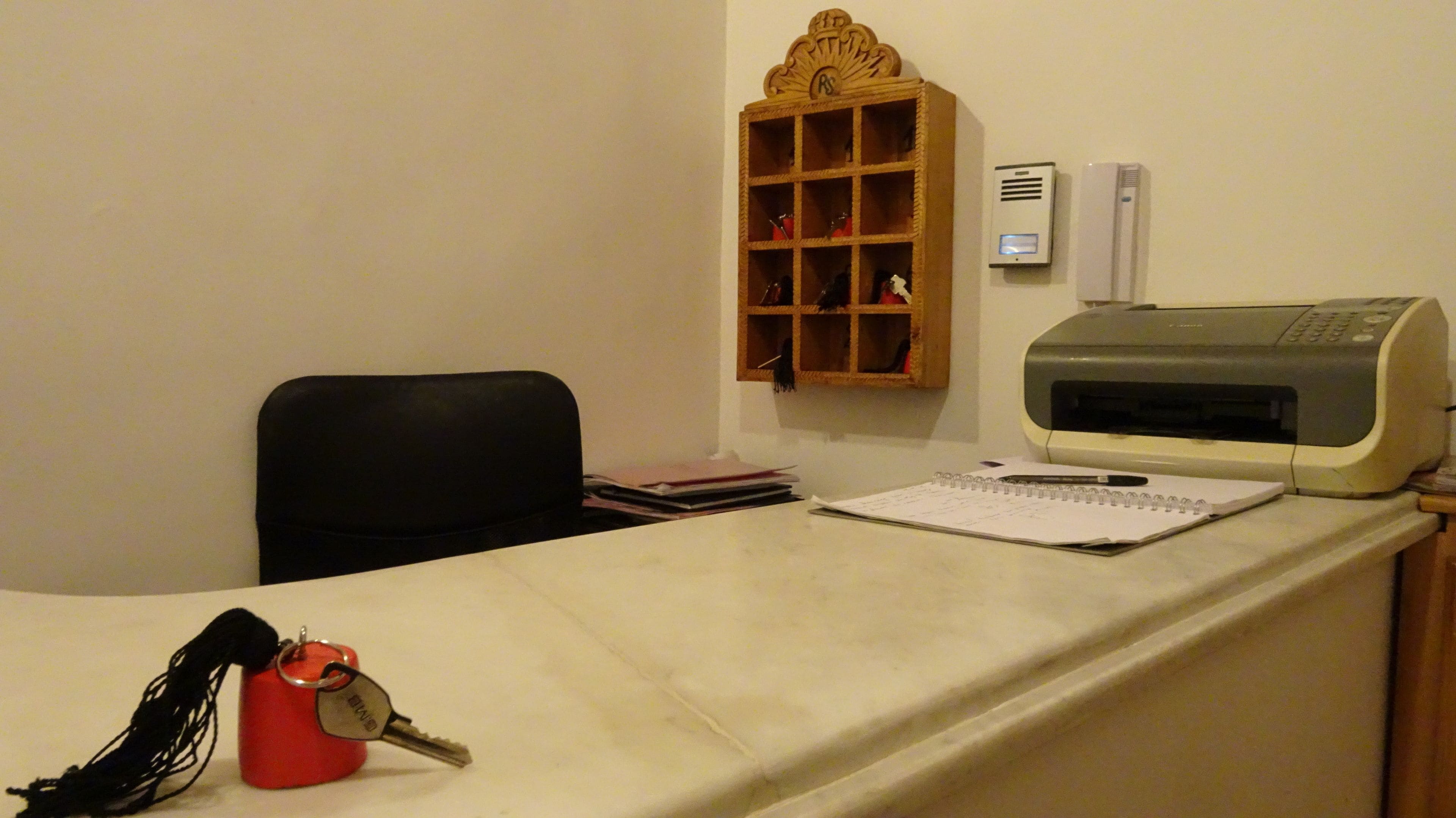 Un bureau avec une imprimante, un bloc-notes, un stylo et un porte-clés rouge.
