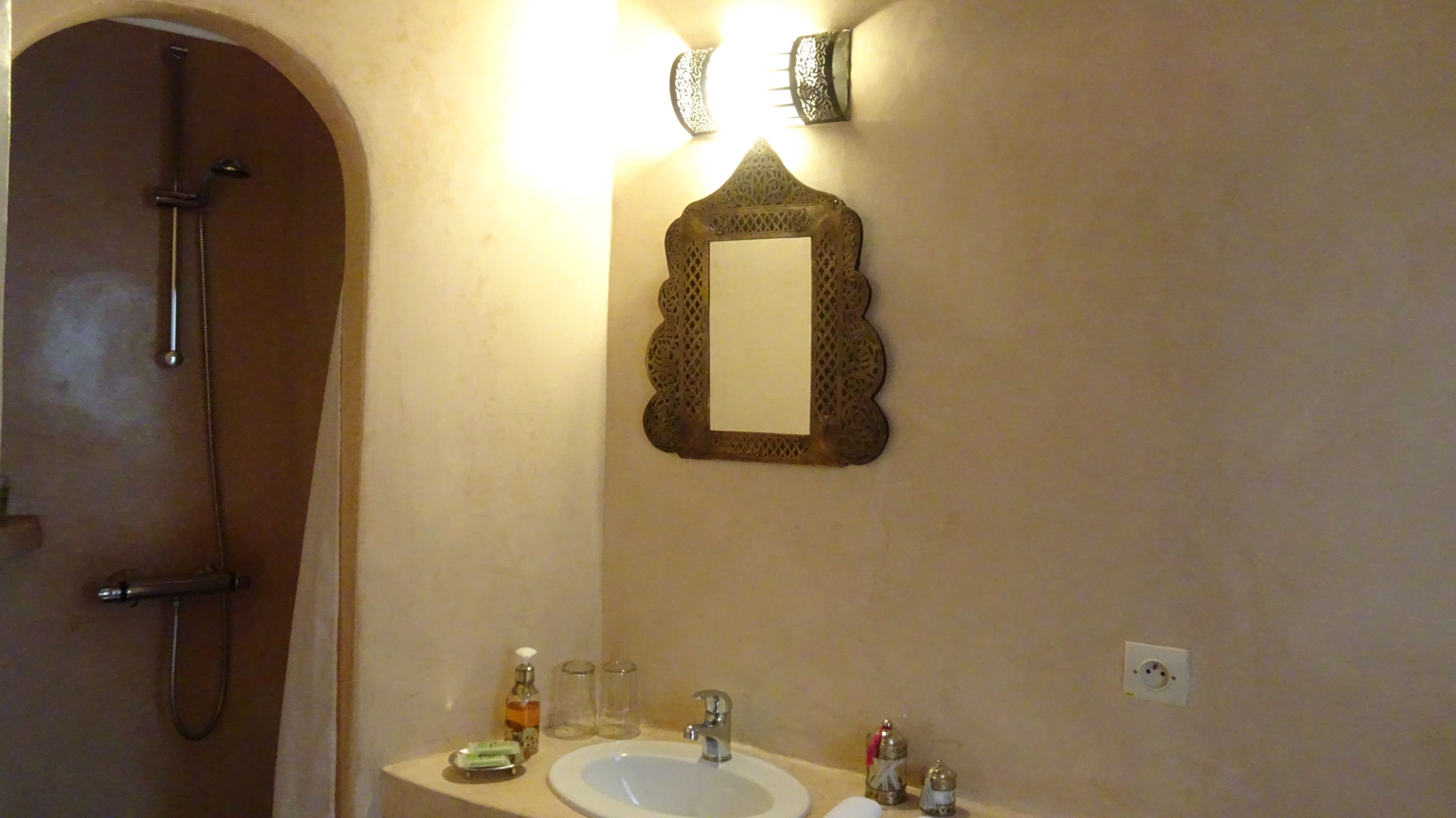 Een badkamer met een douche, een wastafel en een spiegel.