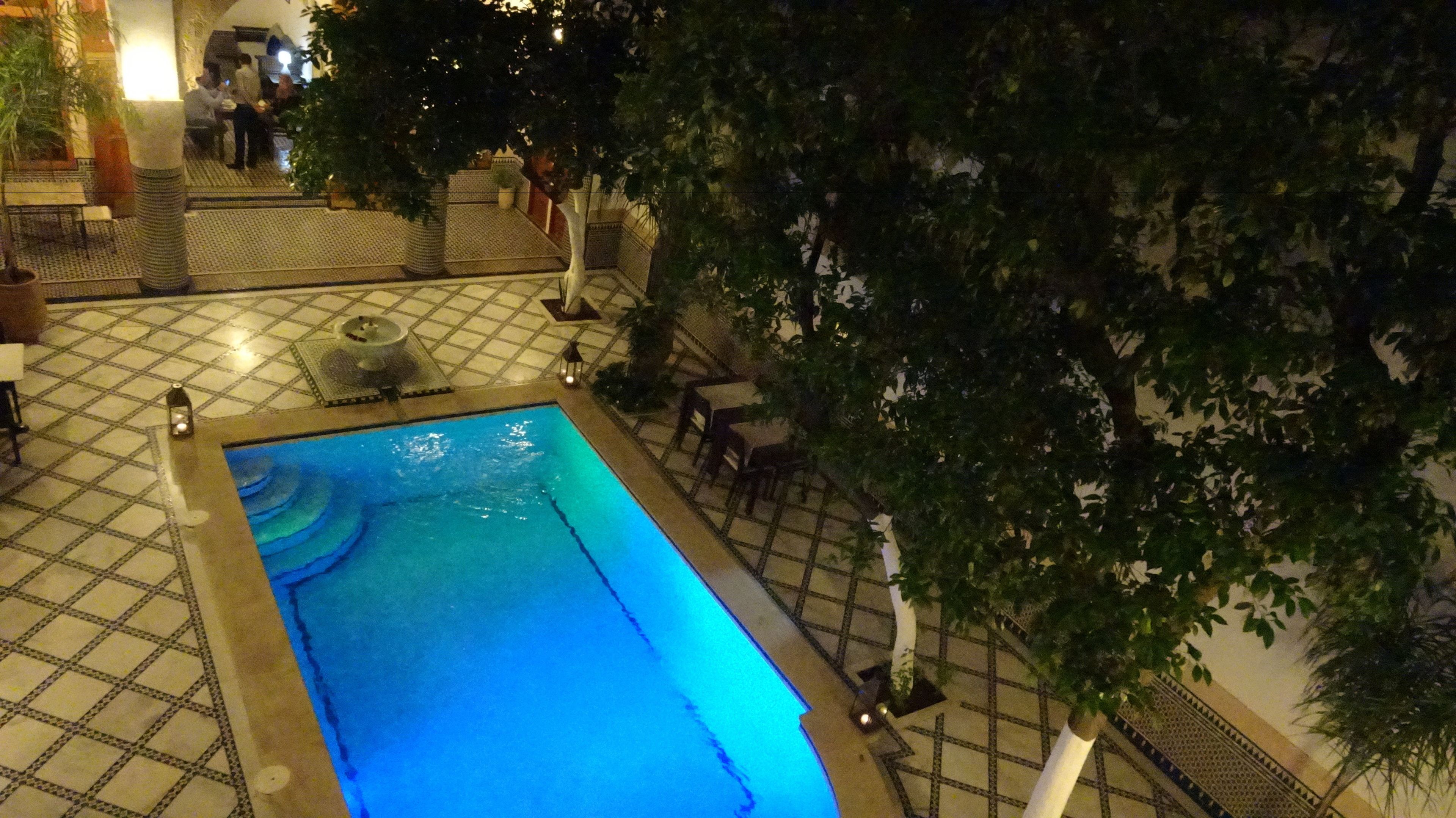 An indoor swimming pool with tiled flooring and seating areas.