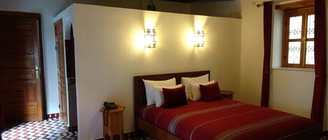 A bedroom with a wooden bed, a patterned floor, and two wall-mounted lights.
