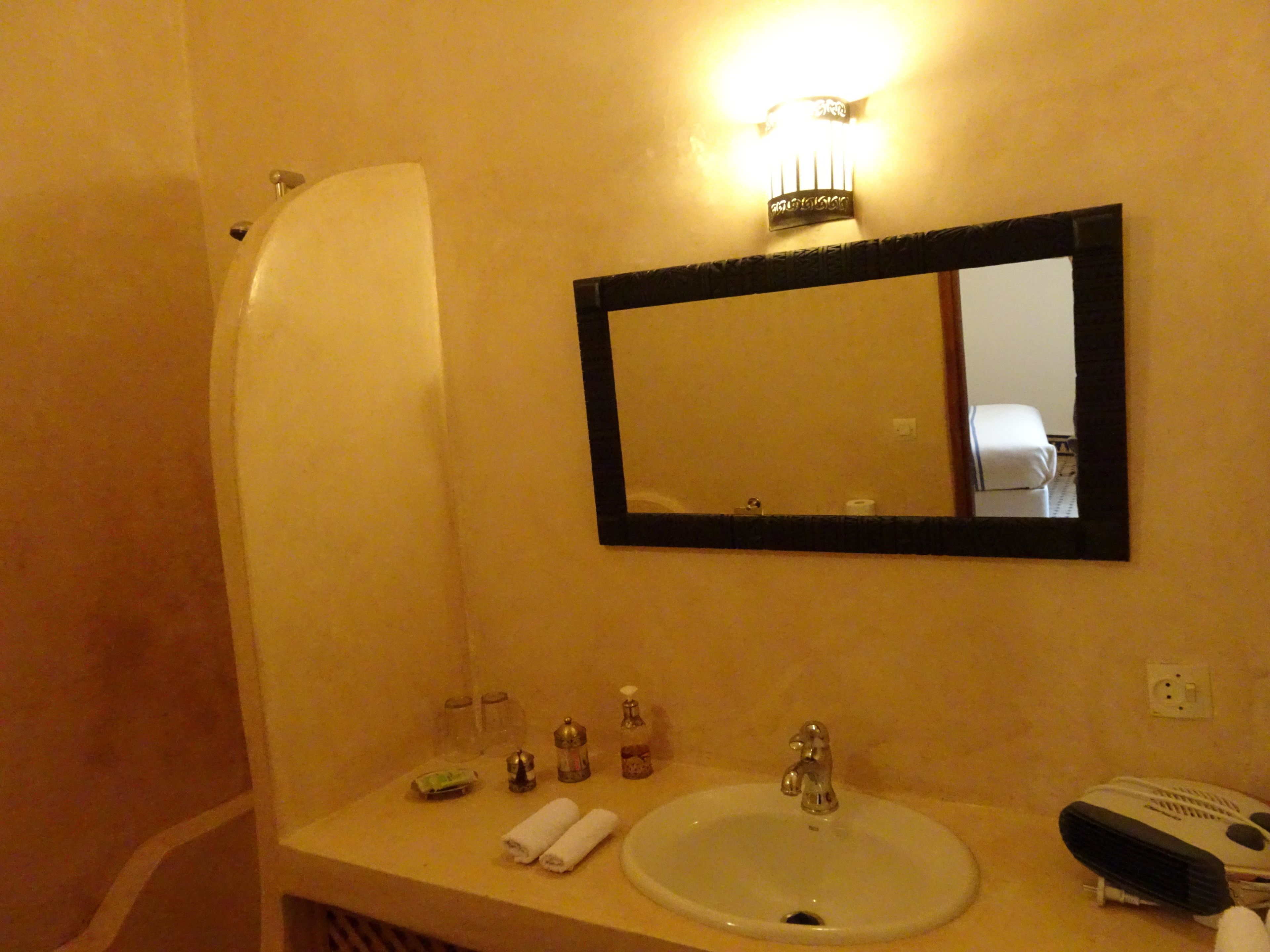 Une salle de bain équipée d’un lavabo, d’un miroir, d’articles de toilette et d’un porte-serviettes.
