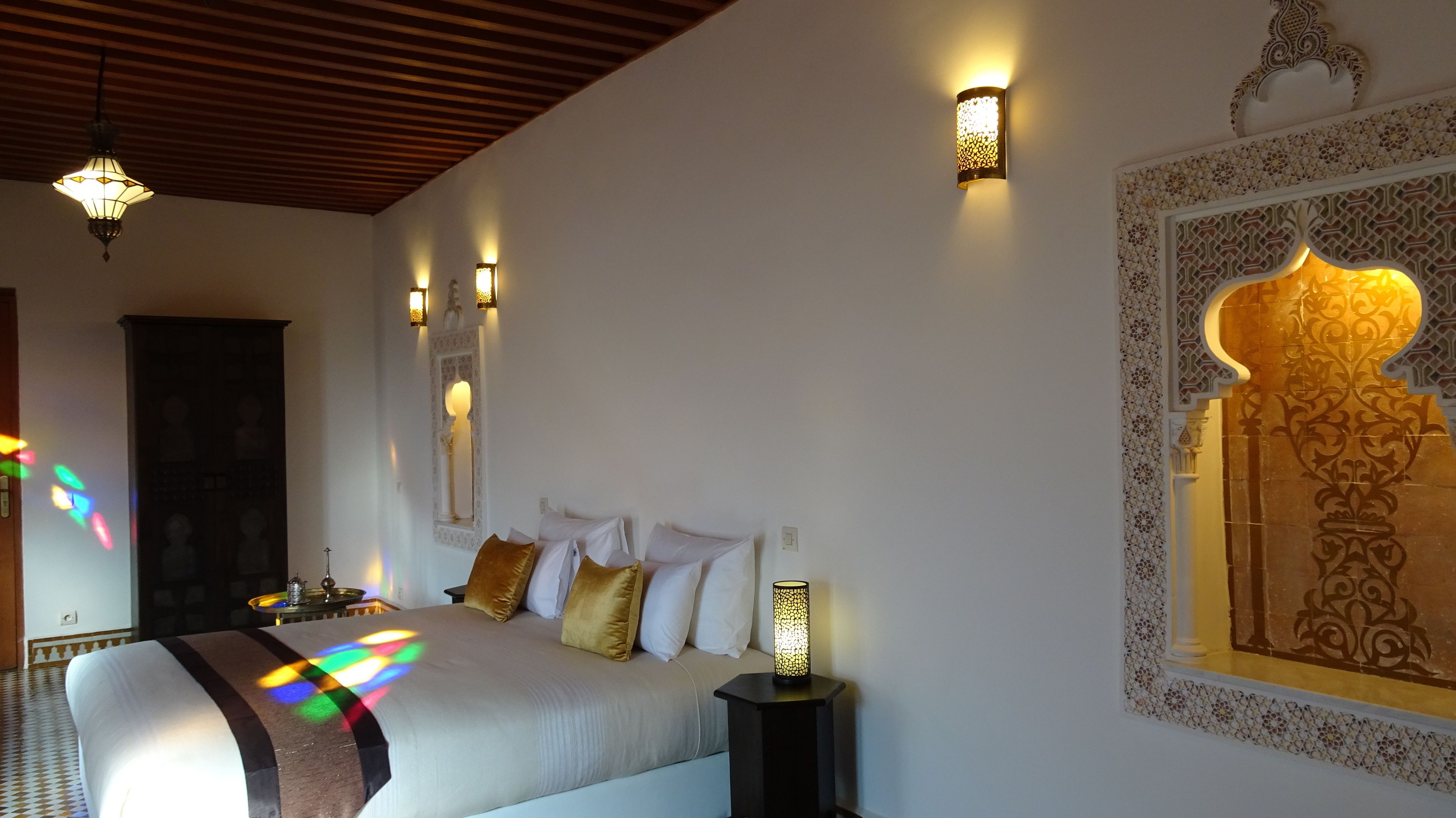 Ein Schlafzimmer mit Bett, Nachttischlampen, einer Wanddekoration und einer Deckenleuchte.