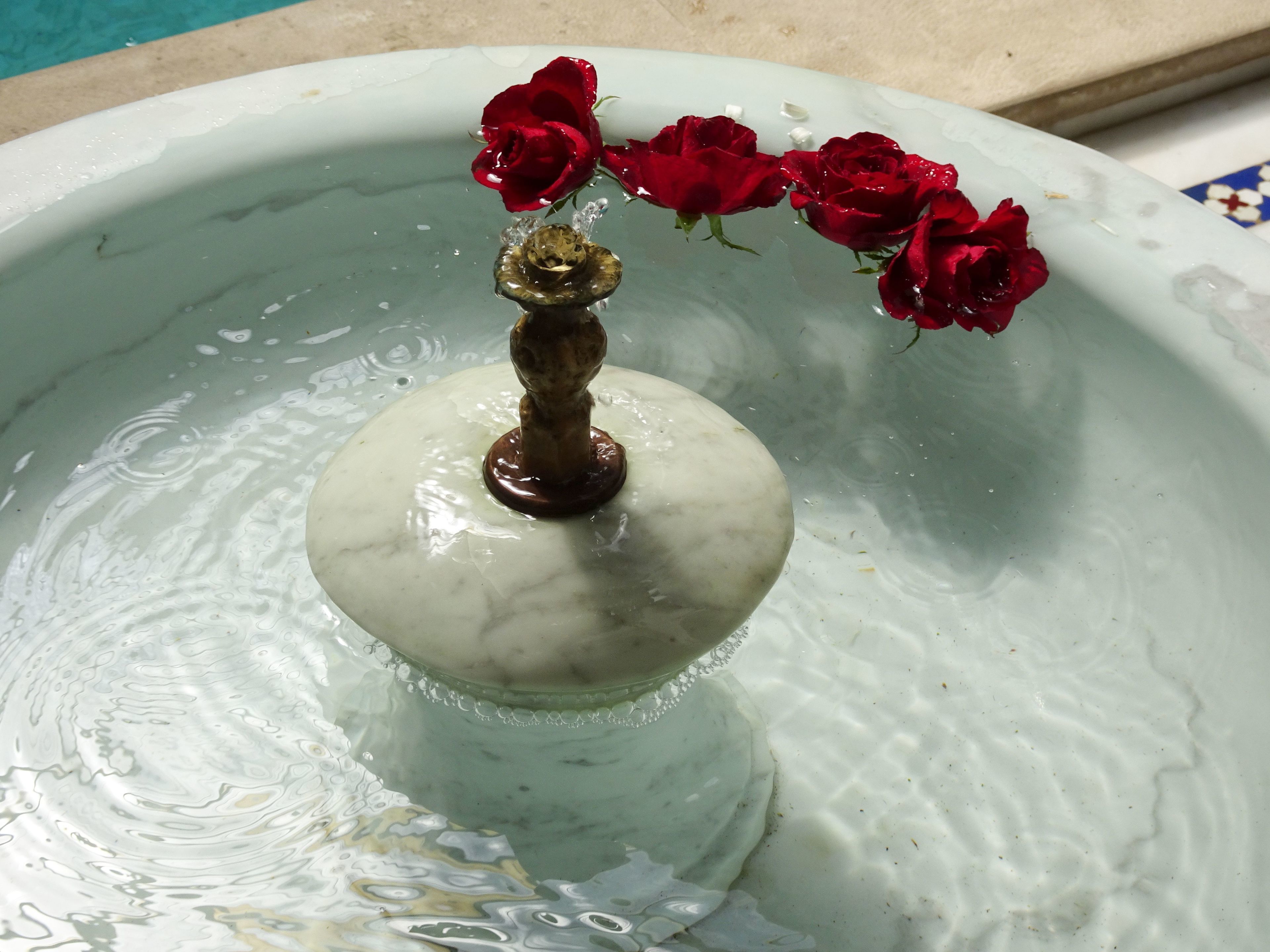 Una fuente de mármol con un arreglo de rosas.