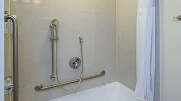 A bathroom with a bathtub, a shower with a handheld showerhead, and a grab bar.