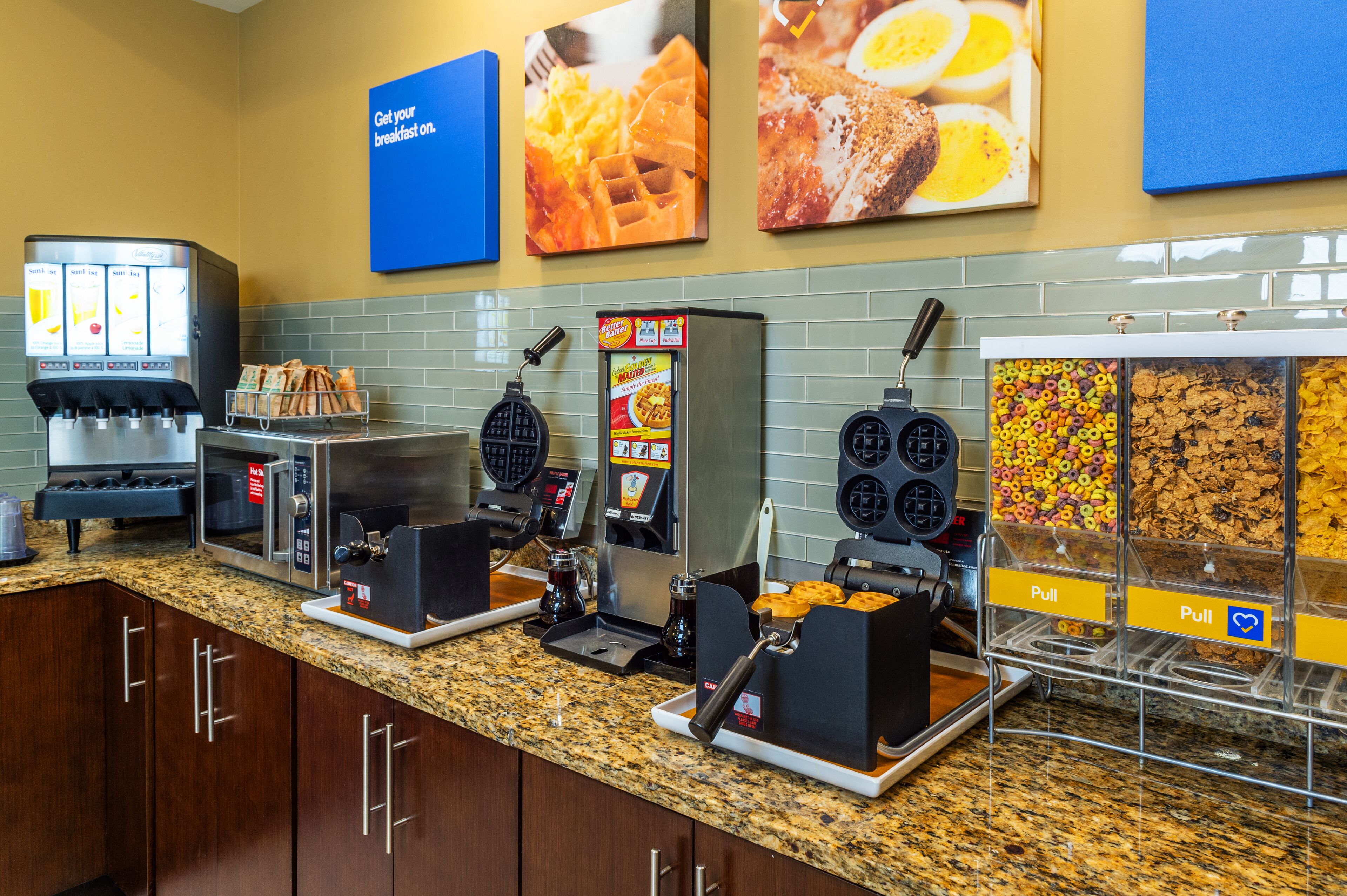 A breakfast bar with waffle makers, a coffee machine, and cereal dispensers.