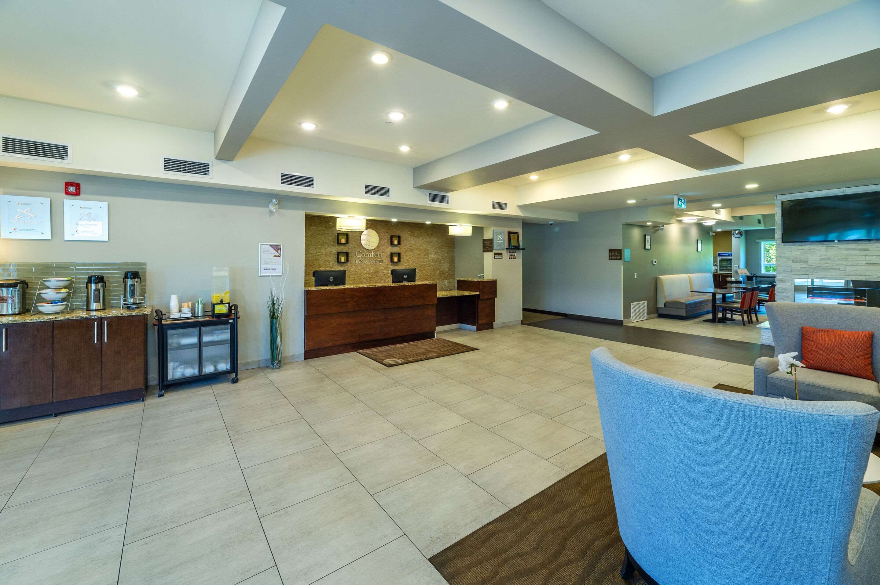 A hotel lobby with a reception desk, seating area, and a kitchenette.