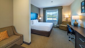 A hotel room with a large bed, a sofa, a desk, and a chair. - Comfort Inn & Suites (Terrace)