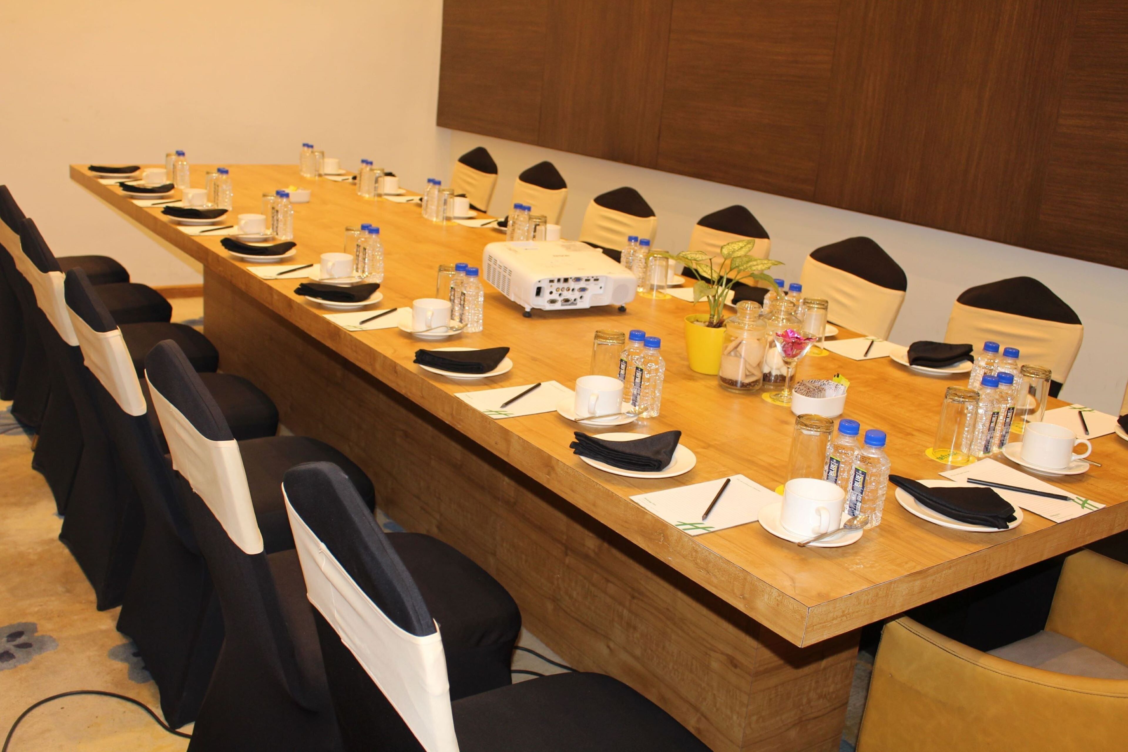 A conference room with a long table, chairs, water bottles, cups, and a projector.