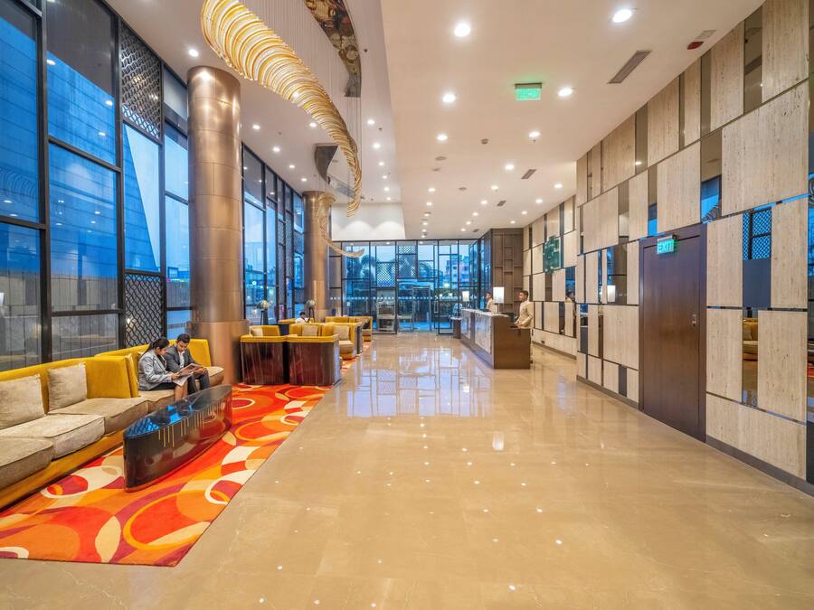 A spacious lobby with a reception desk, seating area, and large windows.