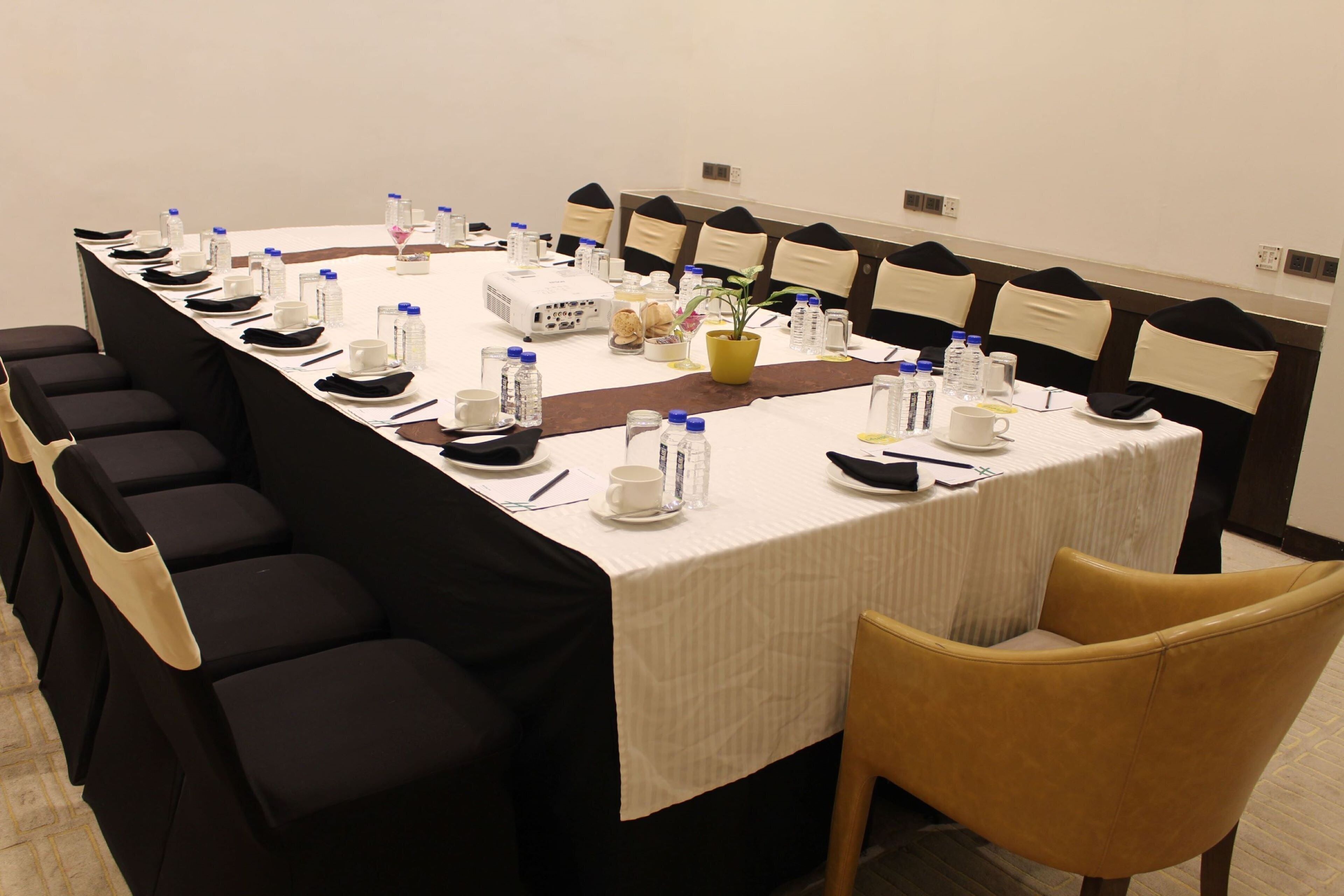 A conference room with a long table, chairs, water bottles, and a projector.