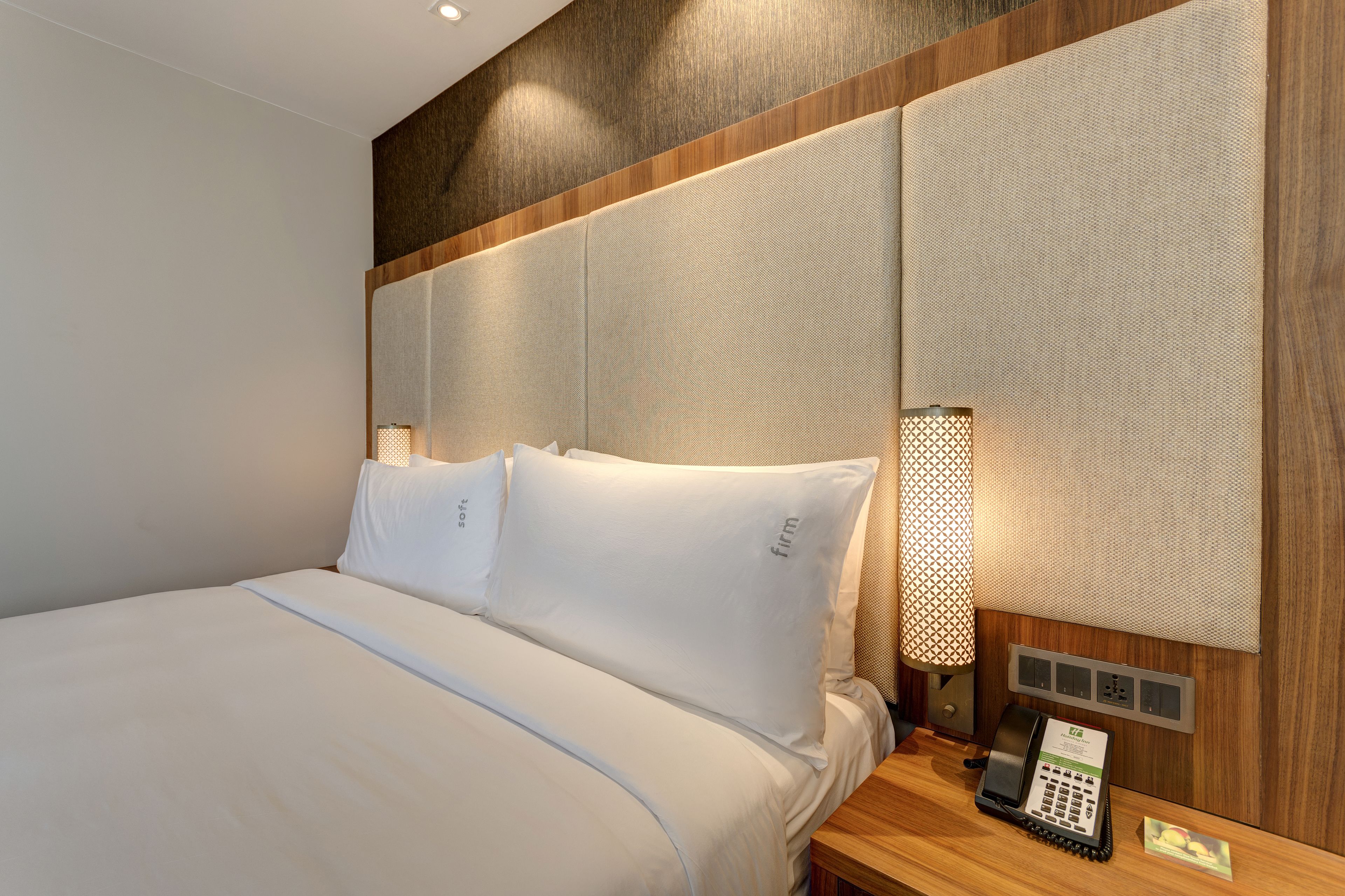 A hotel room with a large bed, a bedside telephone, and a wall-mounted light fixture.