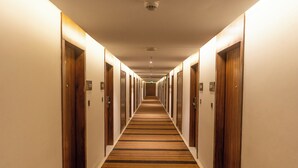 Un pasillo largo y estrecho en un hotel, con puertas de madera a ambos lados y una alfombra a rayas.