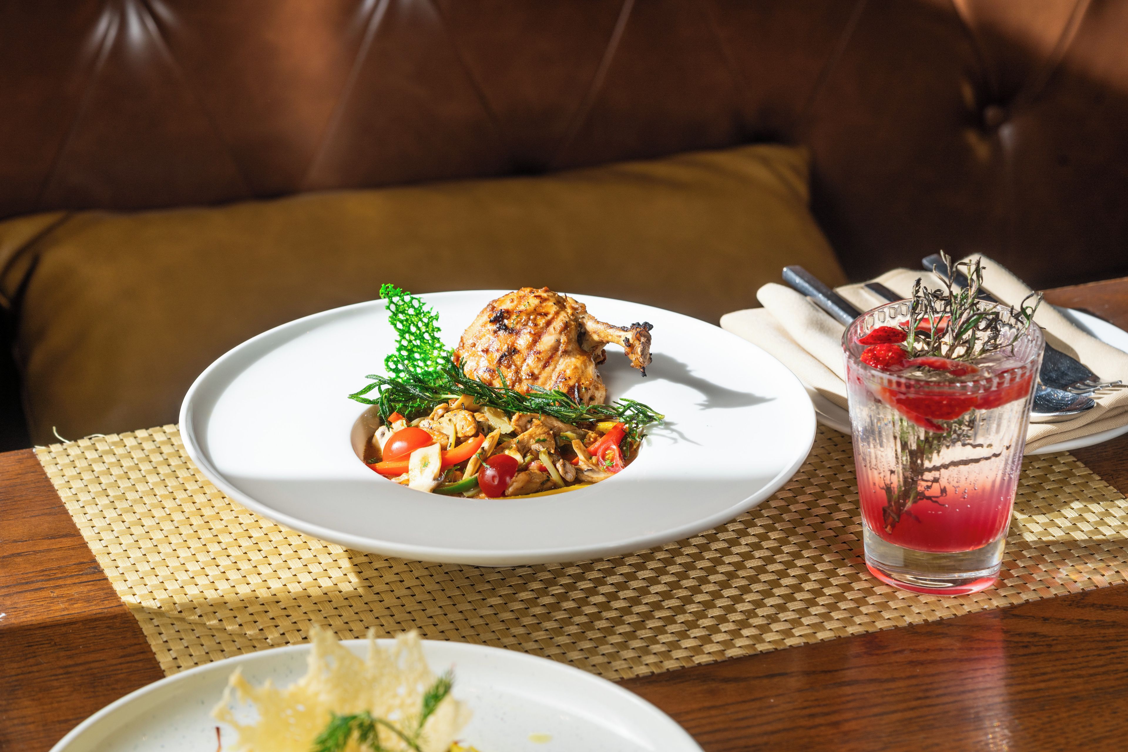 Une table à manger avec une assiette de nourriture, un verre et une serviette, ainsi qu’une fourchette et un couteau.