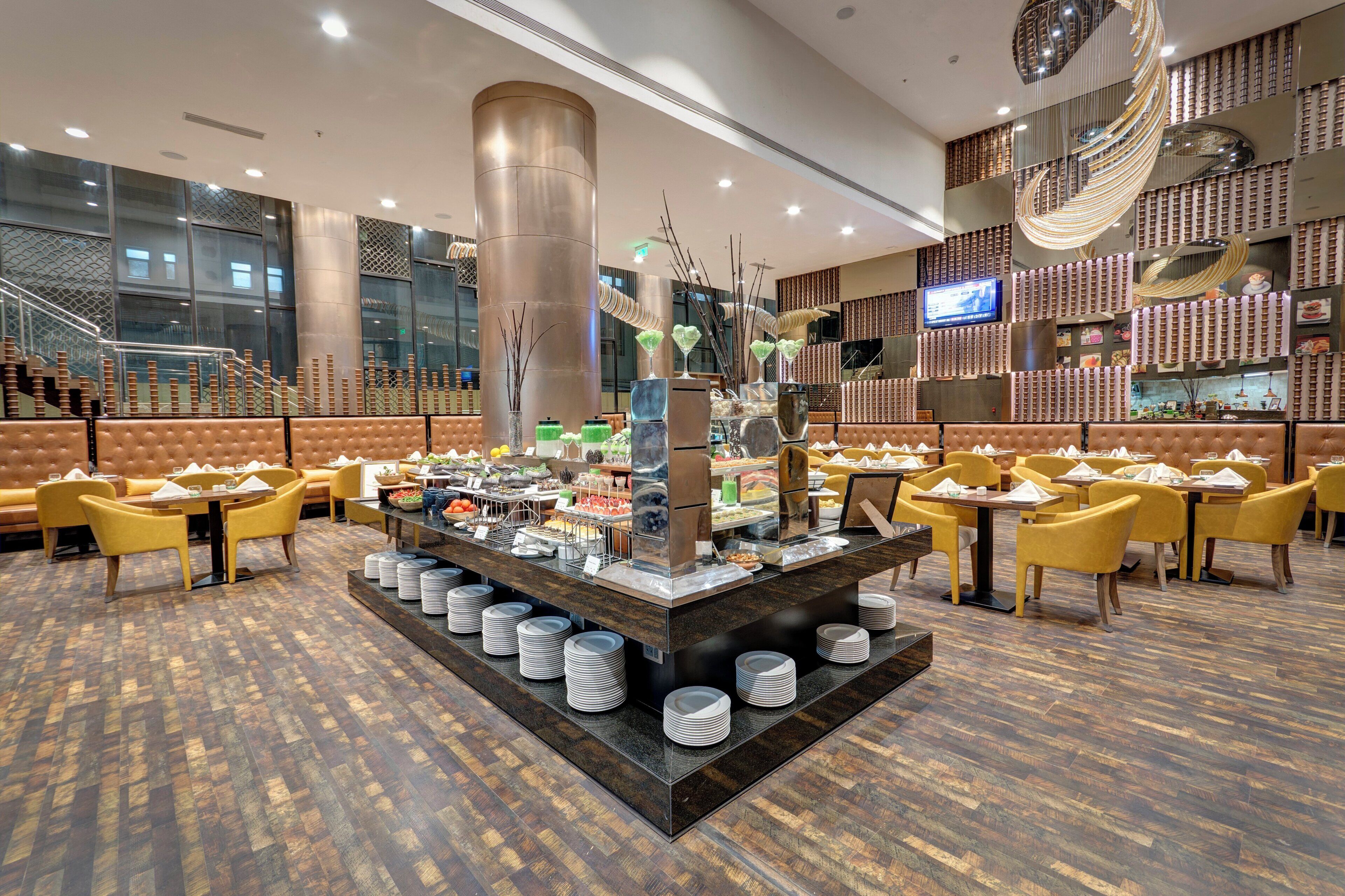 Montaje de bufé con zona de servicio central, diversas opciones de asientos y una decoración interior moderna.