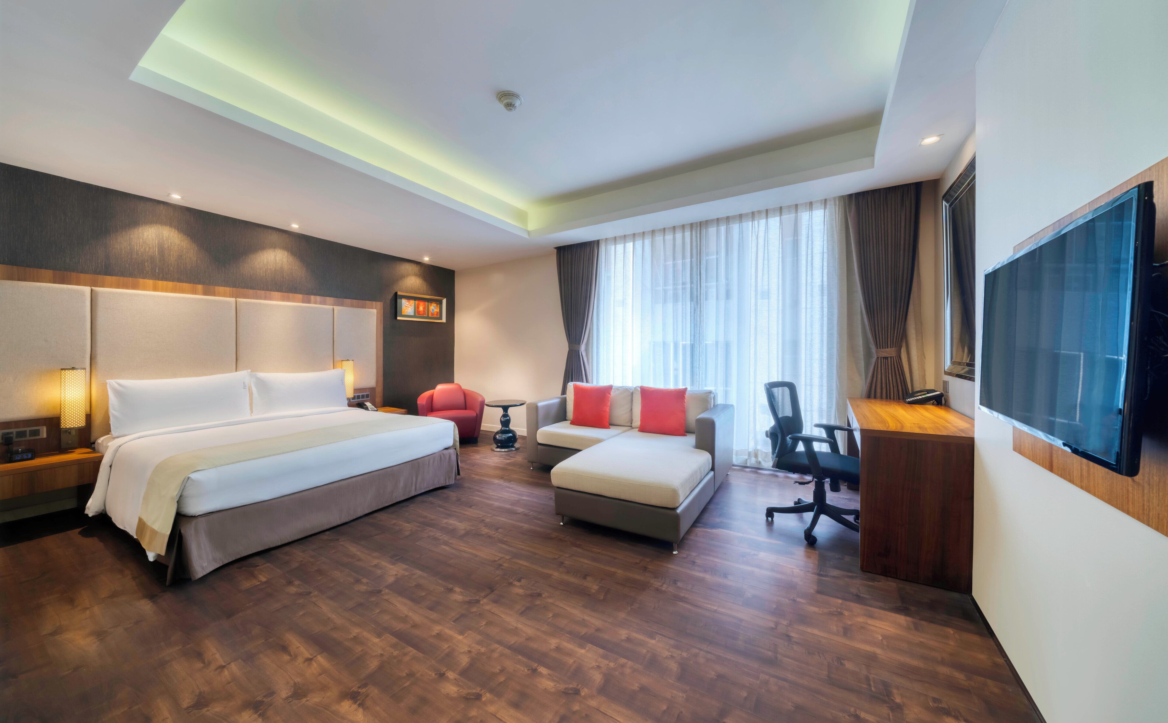 A hotel room with a bed, a sofa, a desk, and a TV.